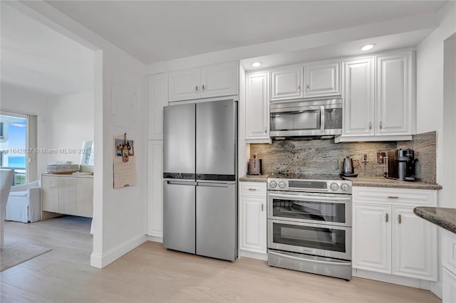 kitchen with white cabinets, decorative backsplash, light hardwood / wood-style flooring, and stainless steel appliances