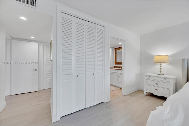 bedroom with light hardwood / wood-style floors, sink, connected bathroom, and a closet