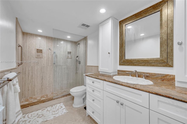 bathroom featuring tile patterned floors, toilet, a tile shower, and vanity