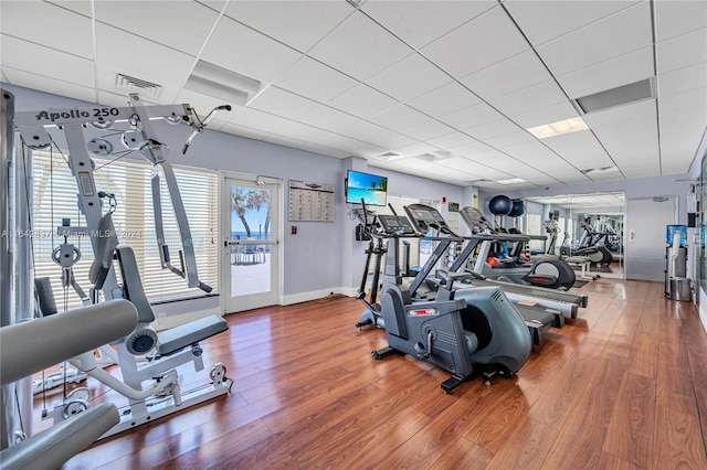 exercise room with a drop ceiling and wood-type flooring