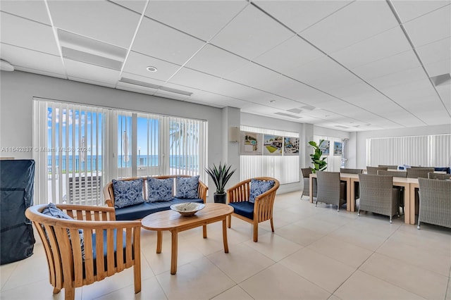 living room featuring a water view, a paneled ceiling, and light tile patterned flooring