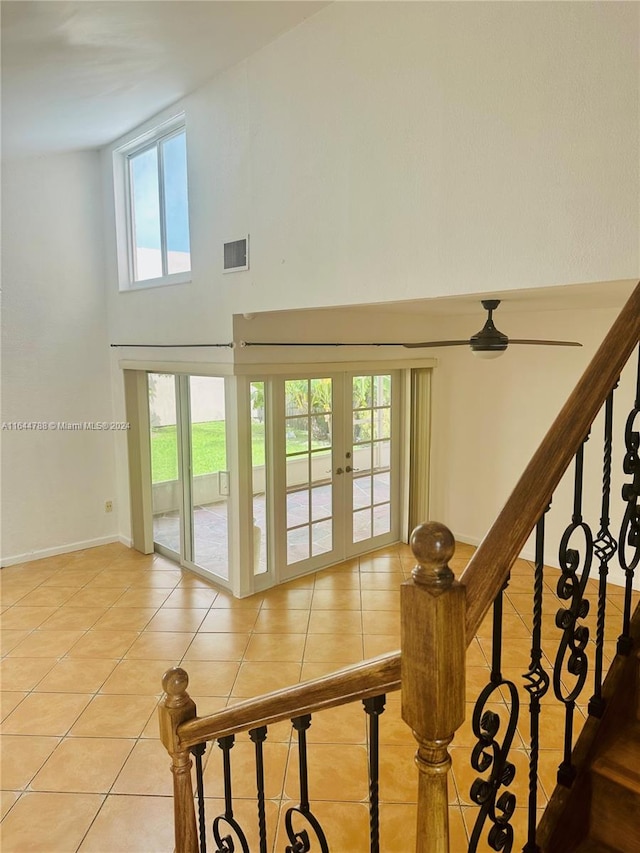 stairway featuring tile patterned flooring, a high ceiling, and french doors