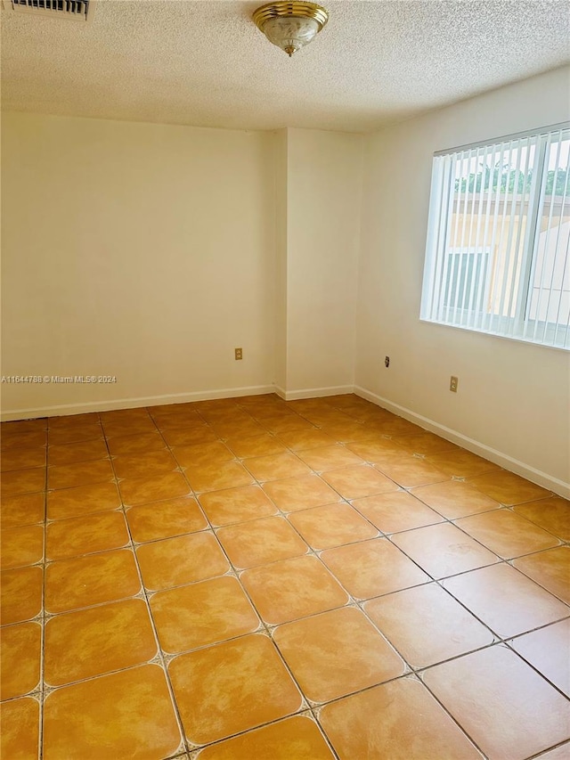 tiled empty room with a textured ceiling