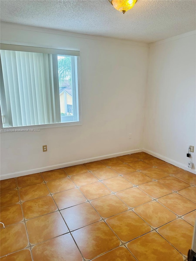 tiled empty room featuring a textured ceiling