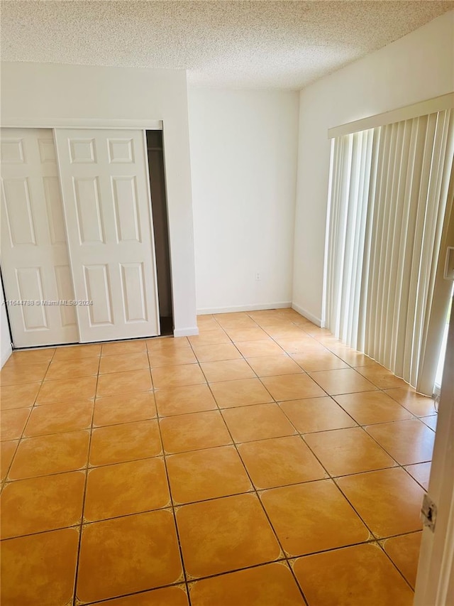 unfurnished bedroom with a closet, light tile patterned floors, and a textured ceiling