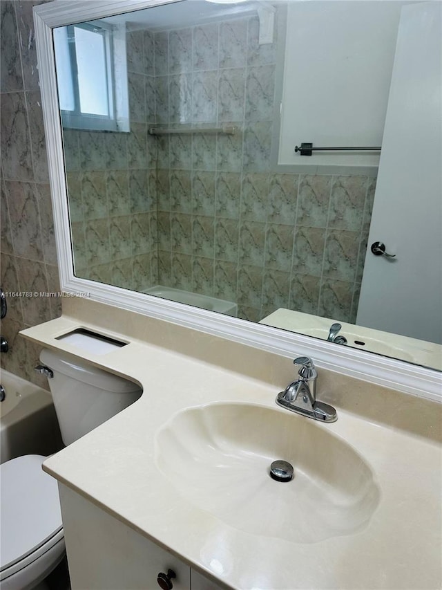 full bathroom featuring tiled shower / bath combo, vanity, and toilet