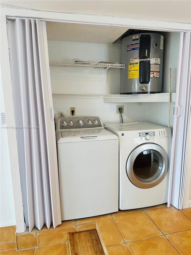 laundry area featuring washing machine and clothes dryer, light tile patterned flooring, and water heater