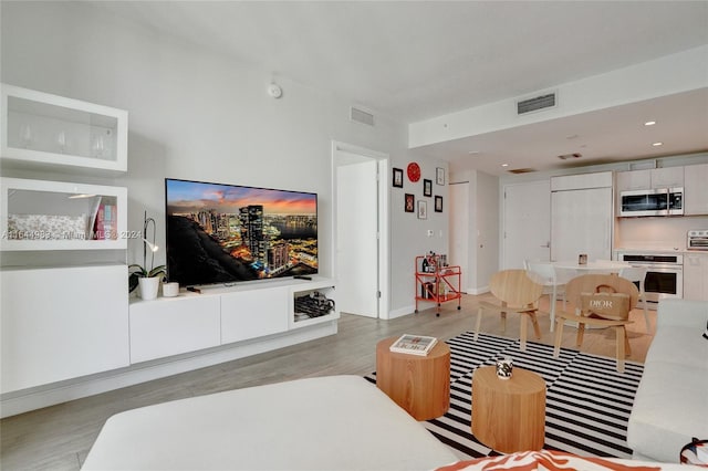 living area with light wood-type flooring, visible vents, and recessed lighting