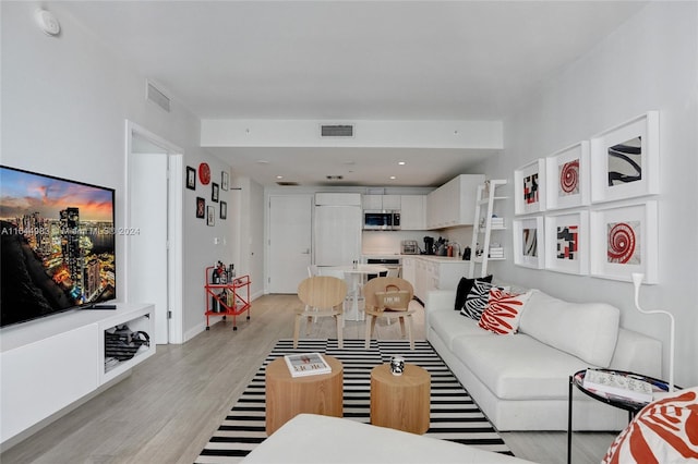 living area featuring light wood-type flooring, visible vents, and baseboards