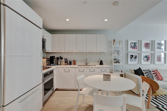 kitchen with light countertops, appliances with stainless steel finishes, a sink, and recessed lighting