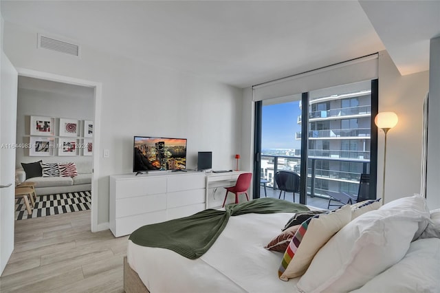 bedroom featuring access to exterior, light hardwood / wood-style flooring, and expansive windows