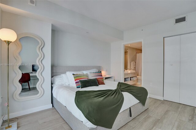 bedroom featuring light hardwood / wood-style flooring, a closet, and ensuite bath