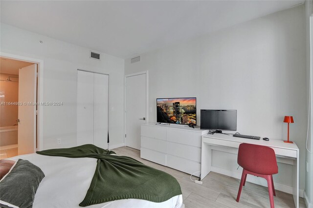 bedroom featuring a closet, built in desk, and ensuite bathroom