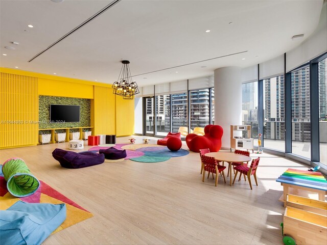 game room featuring a notable chandelier, light hardwood / wood-style floors, and a wall of windows