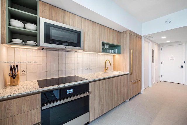 kitchen featuring light stone countertops, sink, light brown cabinets, stainless steel appliances, and tasteful backsplash