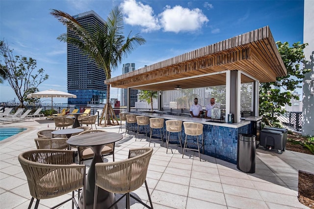 view of patio featuring ceiling fan, a community pool, and an outdoor bar