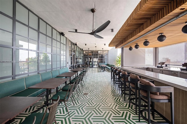 dining room with ceiling fan, a towering ceiling, and a wall of windows