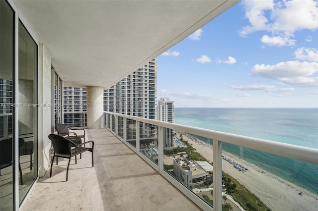 balcony featuring a view of the beach and a water view