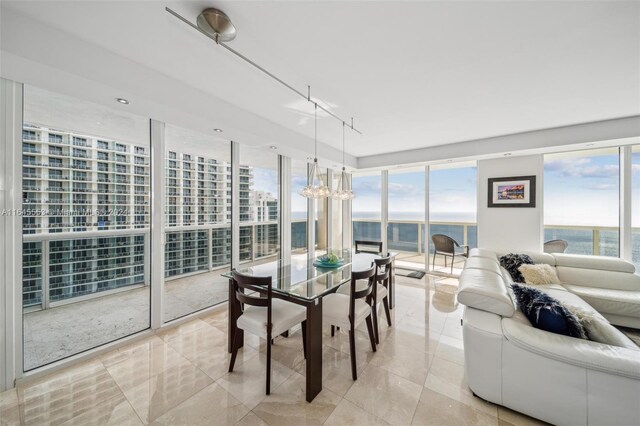 dining room featuring track lighting, a wall of windows, a water view, and light tile patterned floors