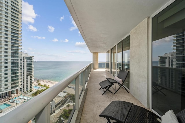 balcony featuring a view of the beach and a water view