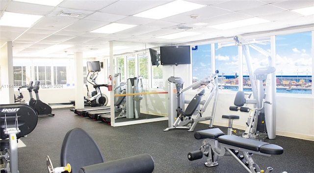 gym featuring visible vents, a paneled ceiling, and baseboards