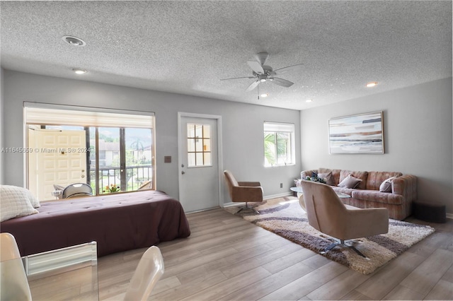 bedroom with a textured ceiling, light hardwood / wood-style flooring, access to exterior, and ceiling fan