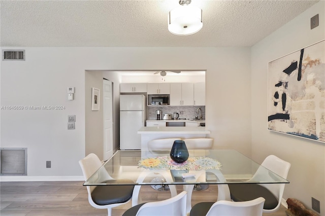 dining area with a textured ceiling, sink, and wood-type flooring