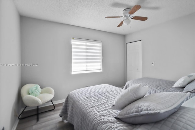 bedroom with a textured ceiling, hardwood / wood-style floors, and ceiling fan