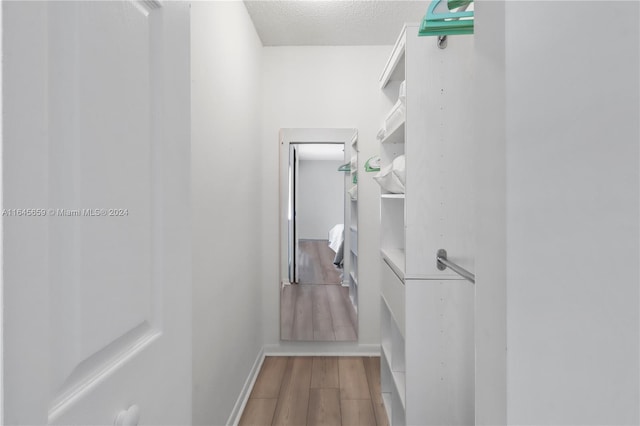 hallway with a textured ceiling and hardwood / wood-style flooring