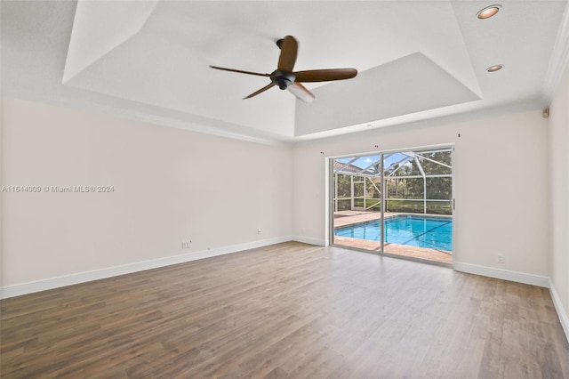 unfurnished room featuring a tray ceiling, ceiling fan, and hardwood / wood-style flooring