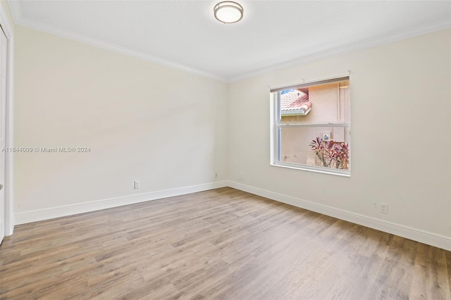 spare room with ornamental molding and light hardwood / wood-style floors