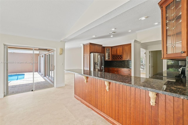 kitchen with a breakfast bar, backsplash, kitchen peninsula, and stainless steel fridge with ice dispenser