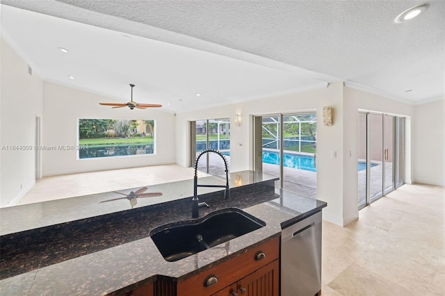 kitchen featuring dishwasher, lofted ceiling, dark stone counters, ornamental molding, and sink