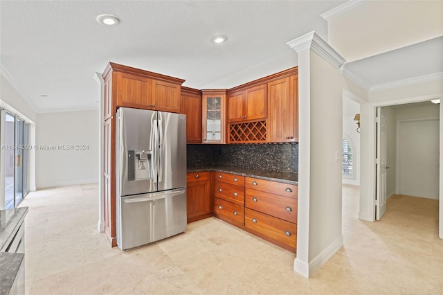 kitchen featuring stainless steel fridge, ornamental molding, tasteful backsplash, a textured ceiling, and dark stone countertops