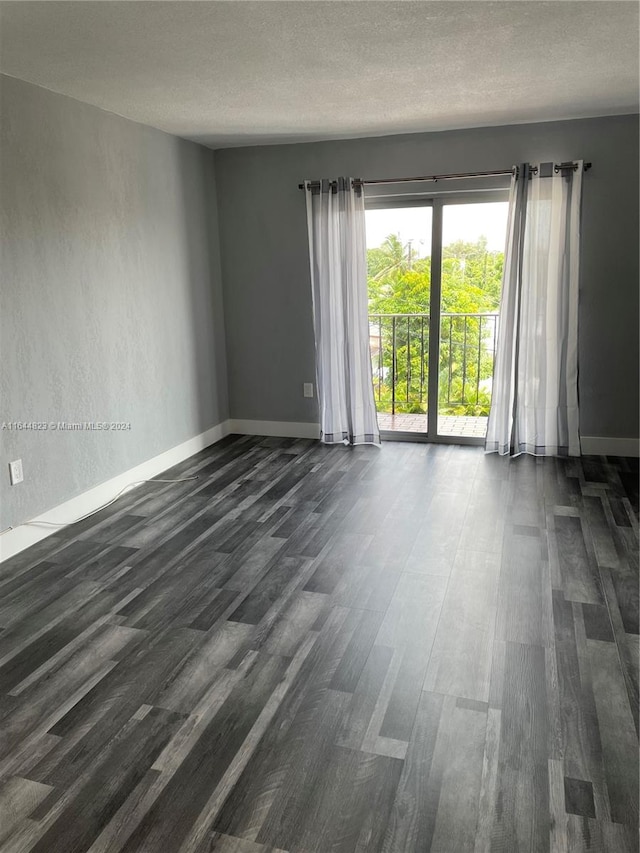 empty room featuring dark hardwood / wood-style flooring and a textured ceiling