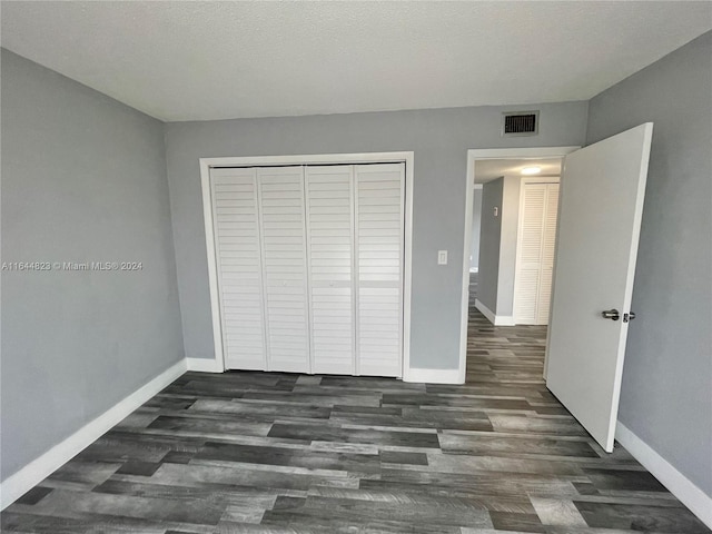 unfurnished bedroom featuring a closet, dark hardwood / wood-style flooring, and a textured ceiling