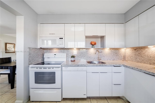 kitchen with light stone countertops, white appliances, white cabinetry, and sink