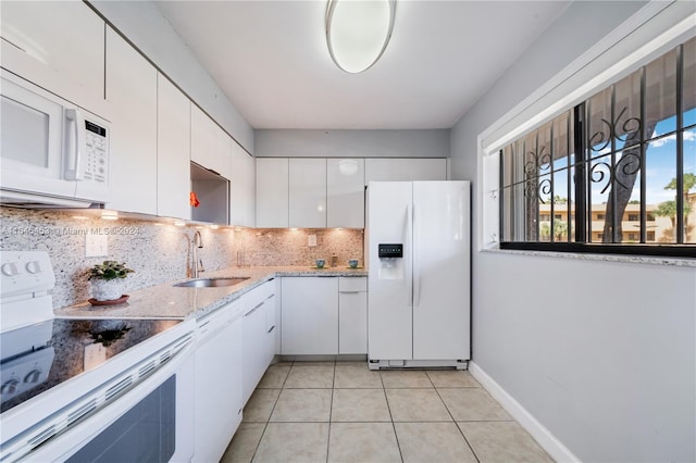 kitchen with white cabinetry, sink, light tile patterned floors, white appliances, and decorative backsplash