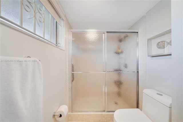 bathroom featuring tile patterned floors, toilet, and a shower with shower door