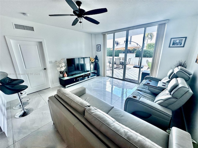 living room featuring ceiling fan and expansive windows