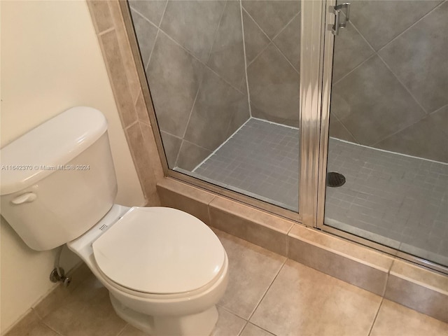 bathroom featuring tile patterned flooring, toilet, and a shower with shower door