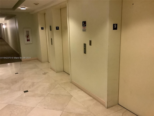 hall featuring light tile patterned flooring and elevator