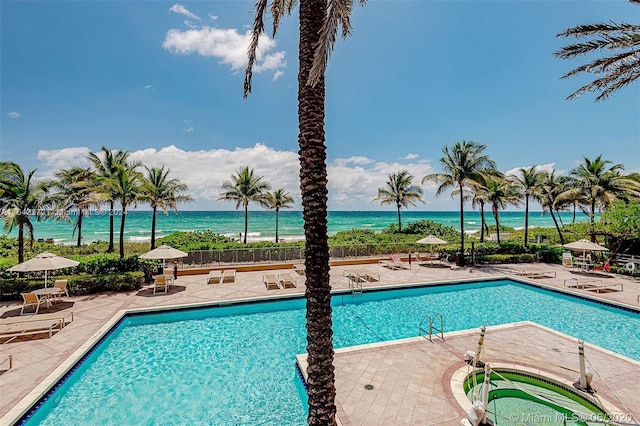 view of swimming pool featuring a patio, a water view, and a hot tub