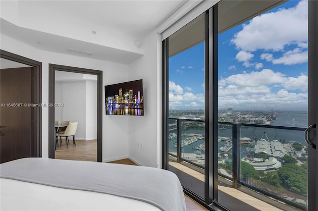 bedroom featuring a water view, hardwood / wood-style floors, and multiple windows