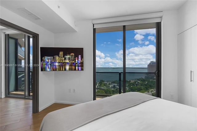 bedroom featuring a water view, hardwood / wood-style flooring, and multiple windows