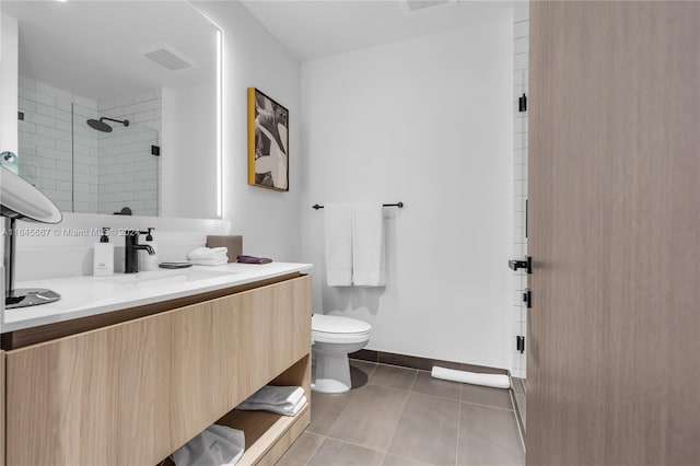 bathroom with tile patterned flooring, toilet, a tile shower, and vanity