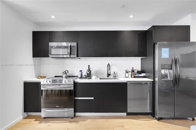 kitchen featuring appliances with stainless steel finishes, tasteful backsplash, light hardwood / wood-style flooring, and sink