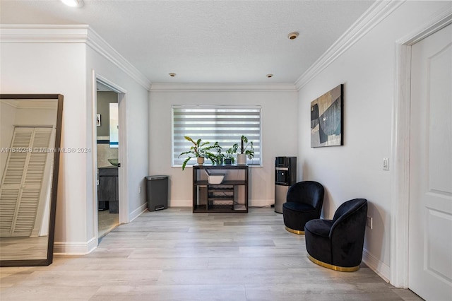 living area featuring a textured ceiling, light hardwood / wood-style flooring, and ornamental molding