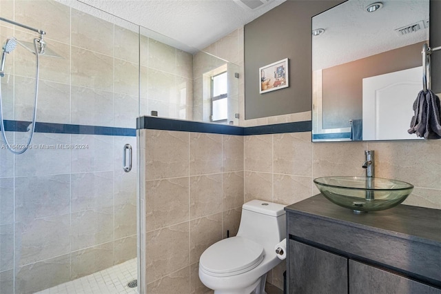 bathroom with tile walls, toilet, an enclosed shower, and vanity