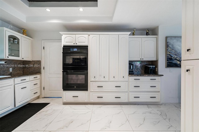 kitchen featuring dark stone countertops, black double oven, and tasteful backsplash